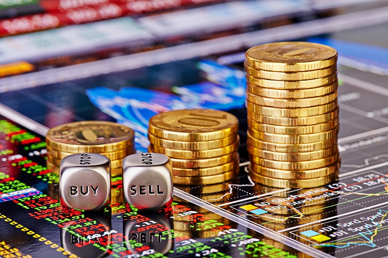 Uptrend stacks golden coins, dices cubes with the words SELL BUY on the financial stock charts as background.