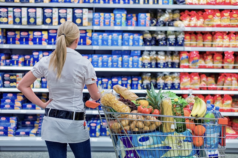 a woman is overwhelmed with the wide range in the supermarket when shopping.
