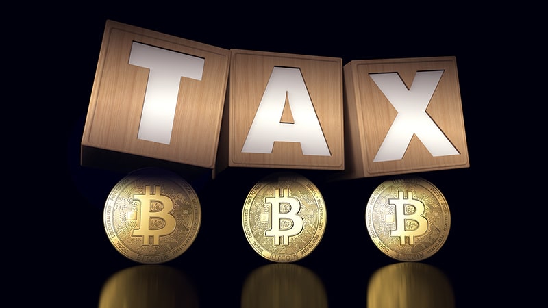 Bitcoin tax concept with wooden blocks and Bitcoins under it.