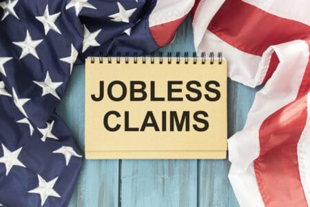 Text jobless claims on page of blocknotes nad USA flag/Business concept.