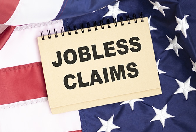 Male hand writing jobless claims on white note