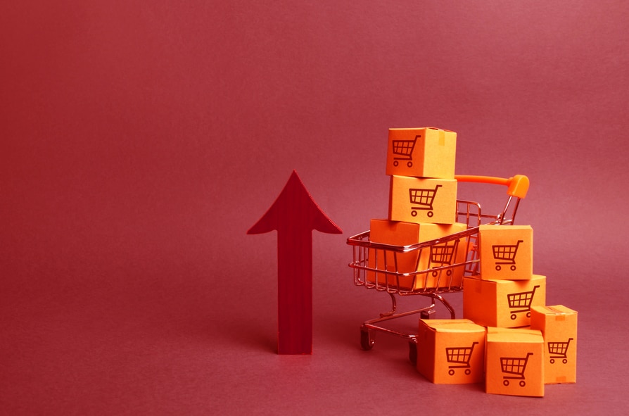 Shopping cart with cardboard boxes with a pattern of trading carts and a red up arrow. Growth wholesale and retail. Improving consumer sentiment, economic growth. Rising prices for goods, inflation