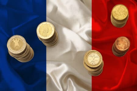 metal euro coins of the EU currency against the background of the national flag of the country of France, the concept of financial development, devaluation, inflation, taxes