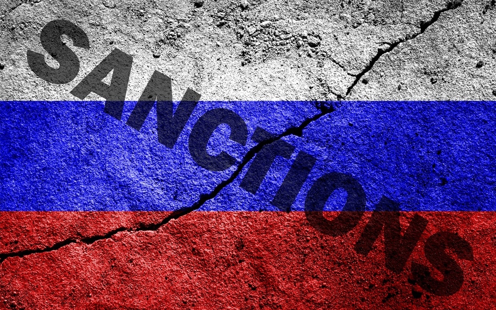 The flag of the Russian Federation on a cracked concrete wall with the words "SANCTIONS". Concept of sanctions against Russia.