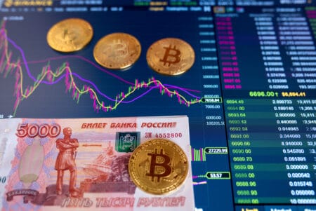 Paper bill Russian Rubles 5000 RUB, blurred background. The electronic schedule of bitcoin on the exchange, volume trades, on monitor lie gold coins bitcoin.