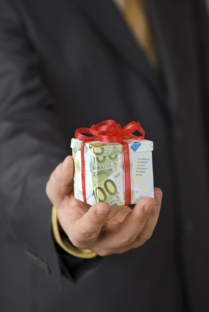 Man offering an expensive gift box wrapped in euro banknotes