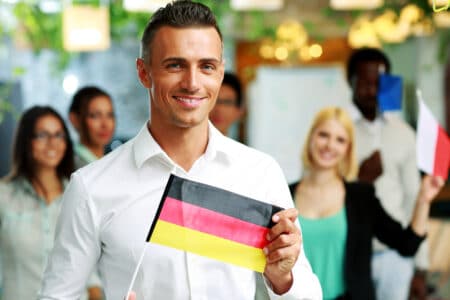 Happy businessman holding flag of Germany in front of colleagues