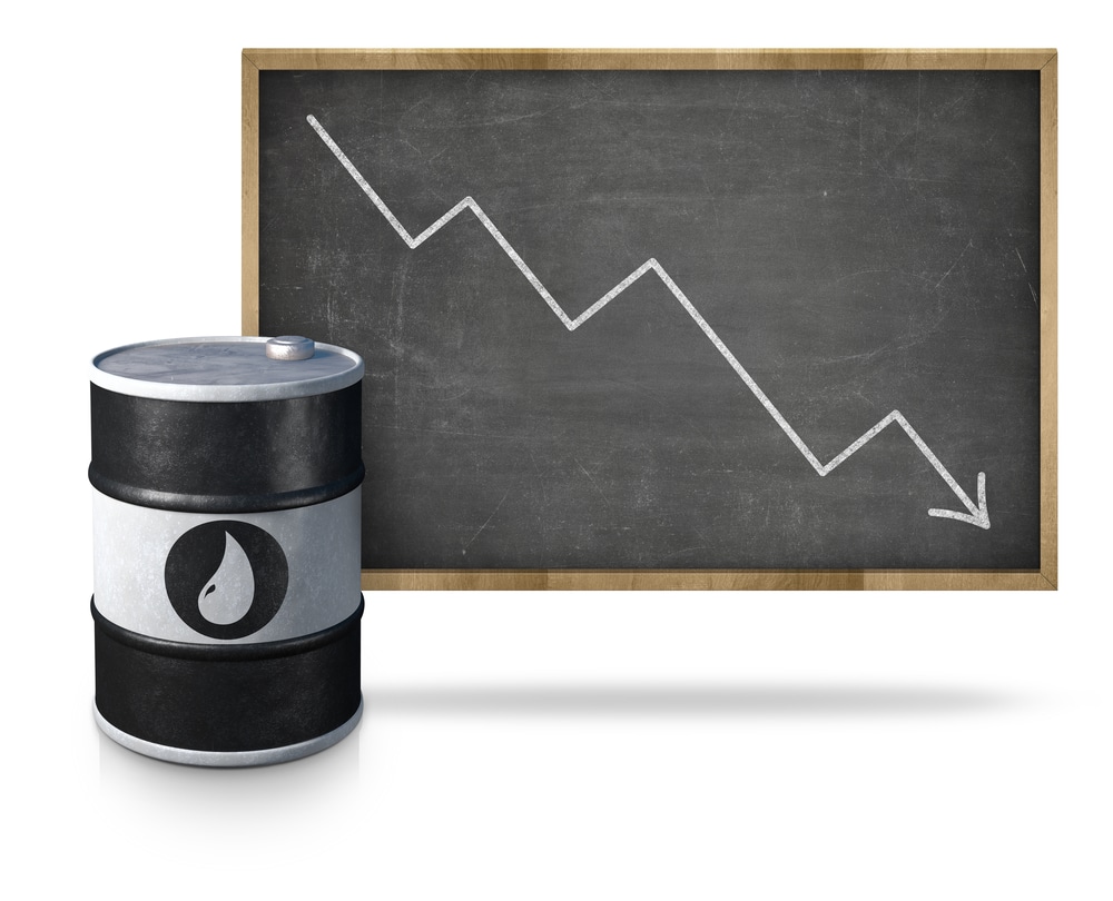 Oil price graph heading down on blackboard with oil barrel