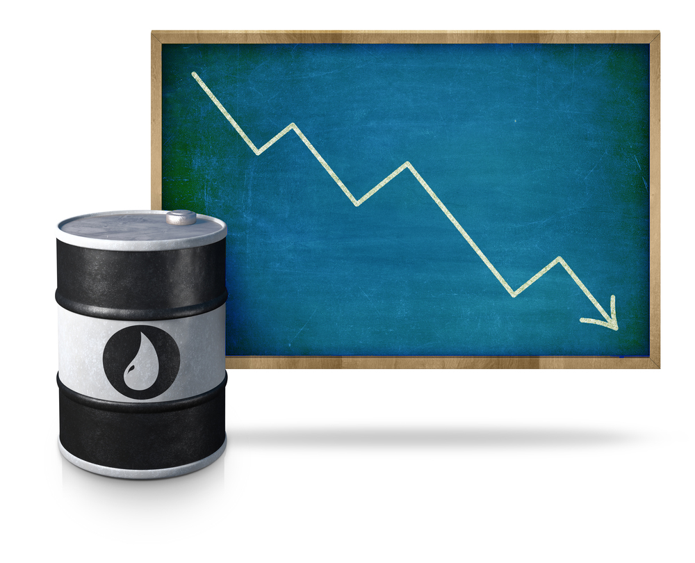 Oil price graph heading down on blackboard with oil barrel