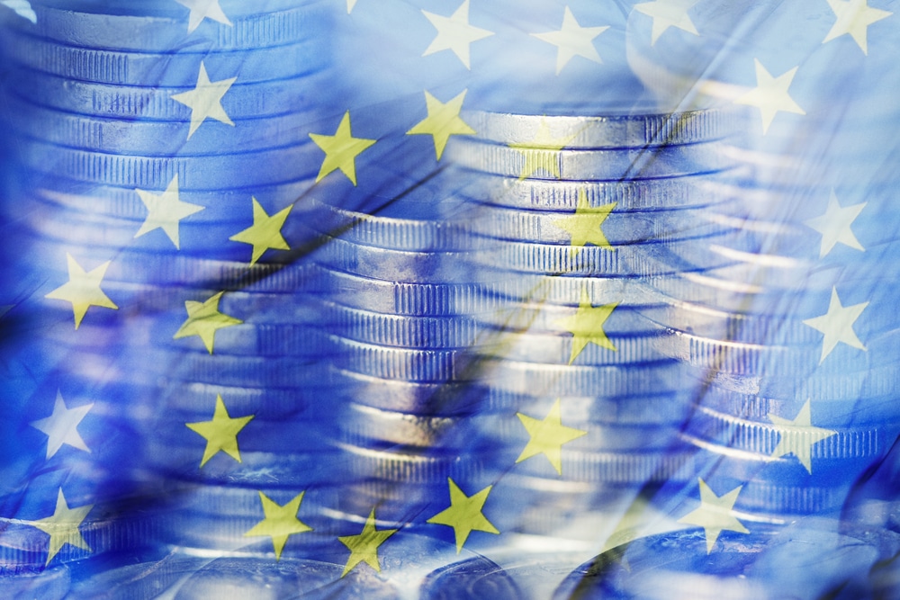 a multiple exposure of some piles of euro coins and a flag of the European Union