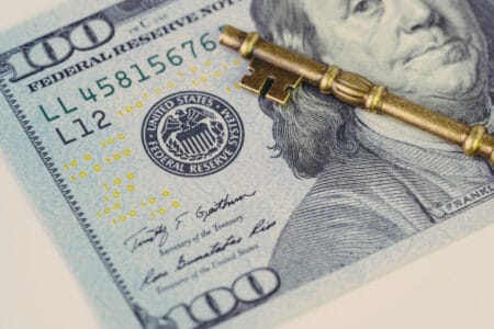 Federal Reserve of US government direction on interest rate concept, vintage bronze key on US Dollar banknote with Feral Reserve emblem.