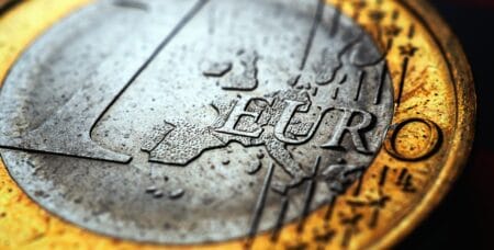 1 euro coin lies on a dark surface. In focus inscription with the name of the Eurozone currency. Close-up. Dramatic illustration with increased contrast and saturation about the European Union. Macro