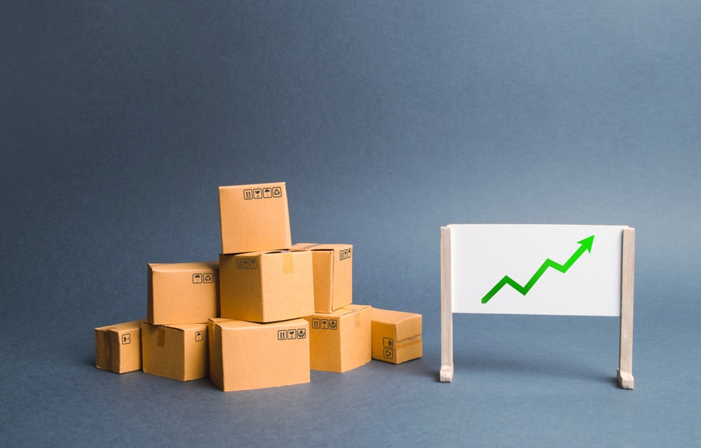A pile of cardboard boxes and stand with green up arrow. Price increase. The growth rate of production. Increasing consumer demand. exports and imports rise. Growth of income from the sale of goods.