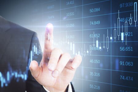 Close up of businessman hand pointing at abstract glowing grid with index and candlestick forex chart. Trade and financial data concept. Double exposure