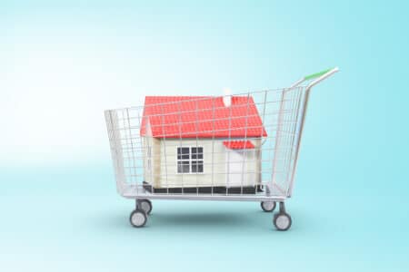 Trolley with red house on blue background. Concept of buying property. 3D Rendering